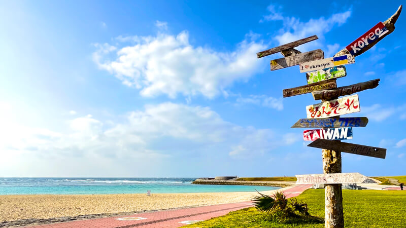 沖縄県宜野湾市トロピカルビーチの写真。空と海のコントラストがきれい。写真に映る看板はポケモンGOのポケスポットにもなったとか。